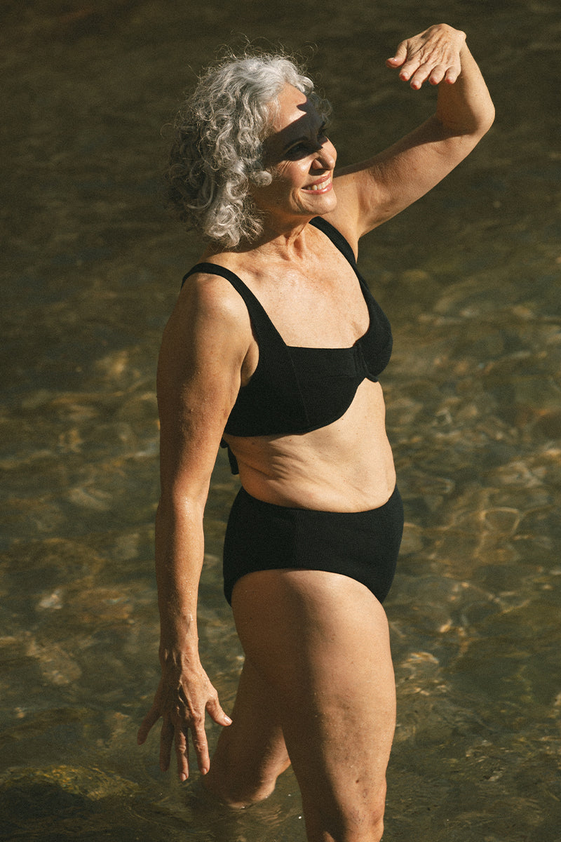 Older woman in the sea wearing Black Bikini AQVA Swimwear