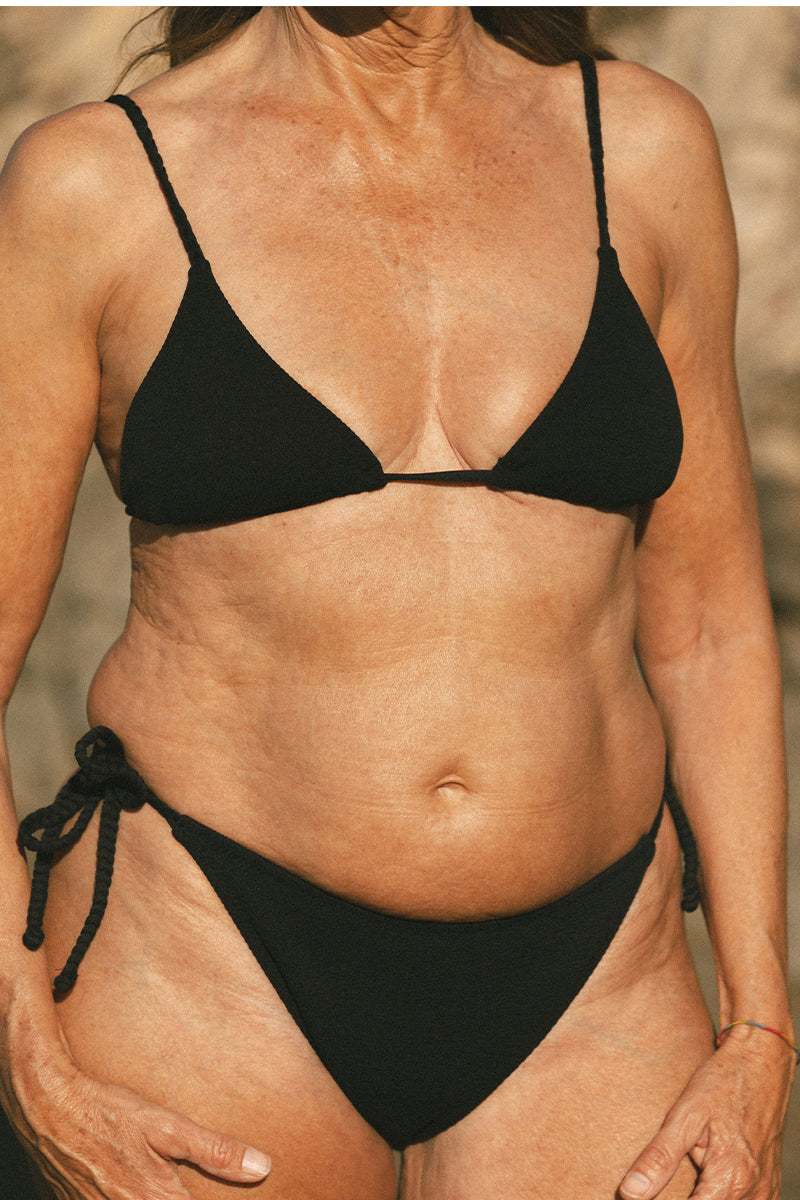 Older model on the beach wearing Black Tie Bikini AQVA Swimwear