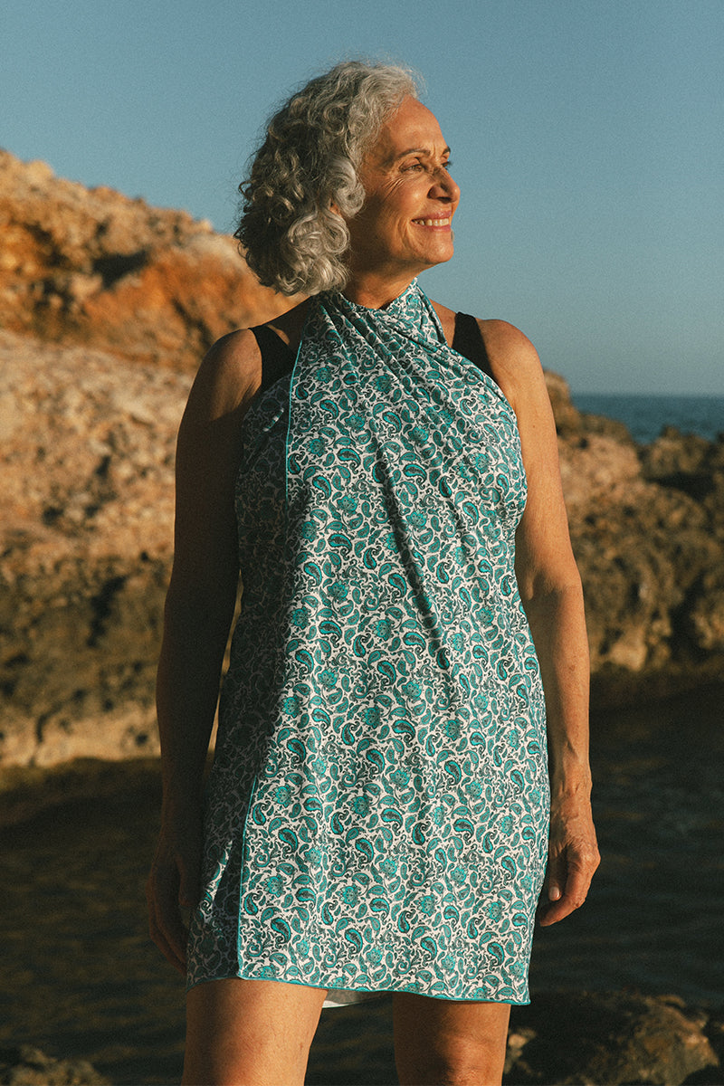 Older female model on the beach wearing a blue pareo AQVA Swimwear