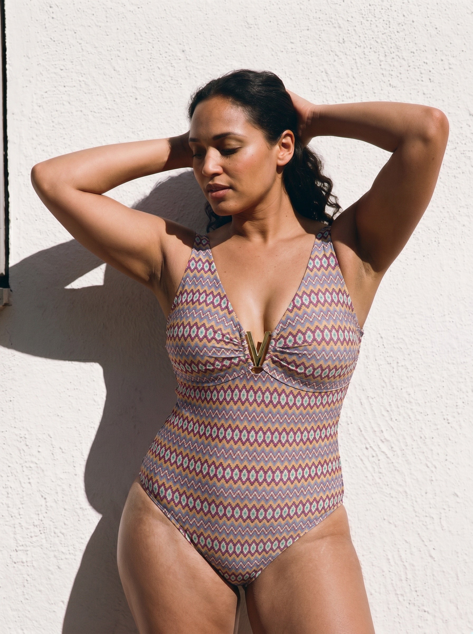Curvy Woman wearing a patterned swimsuit against a white wall, xl and xxl sizes